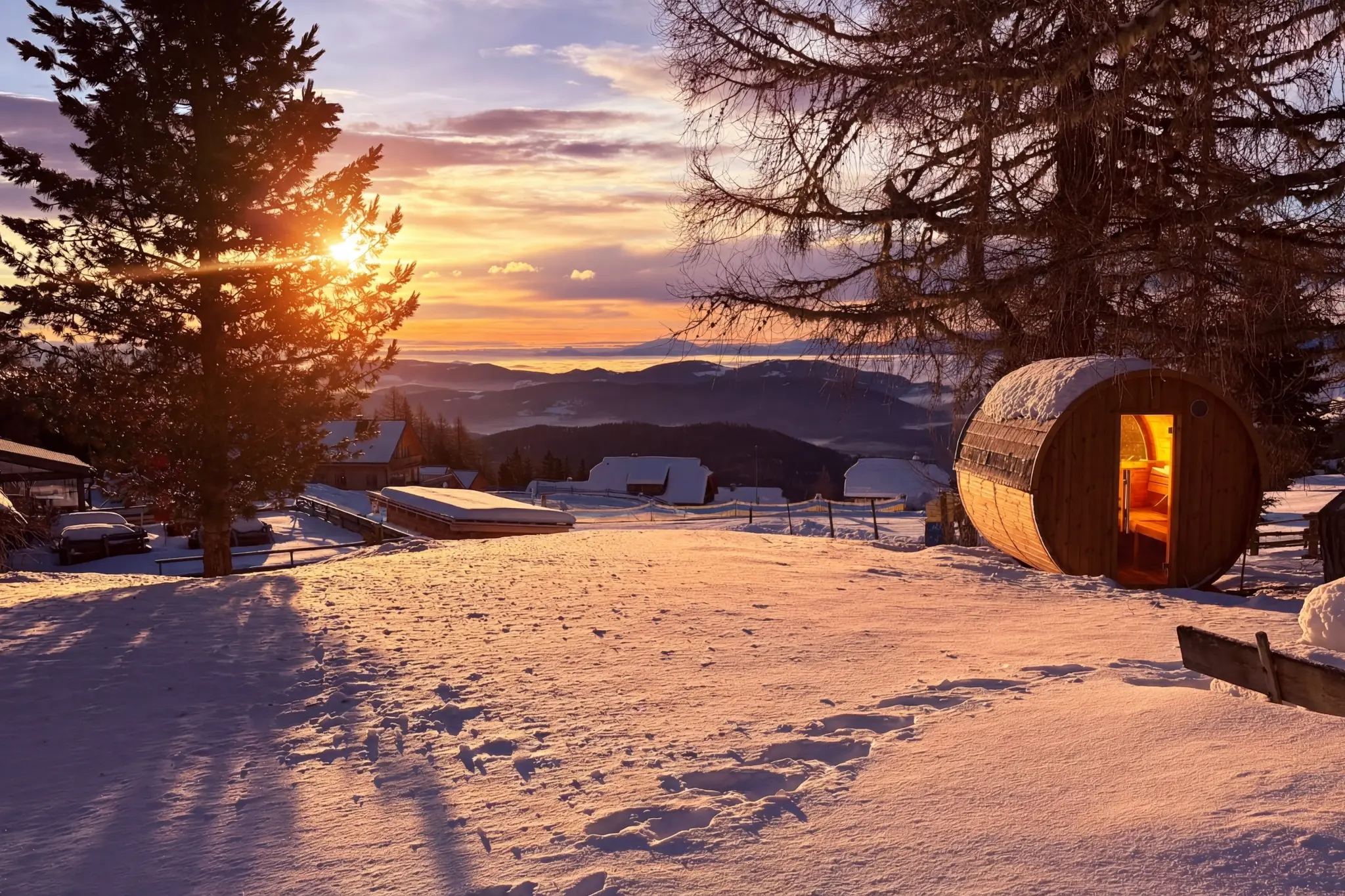 Private Fasssauna der Berglodge Hochrindl bei Sonnenuntergang mit Bergpanorama über den Nockbergen