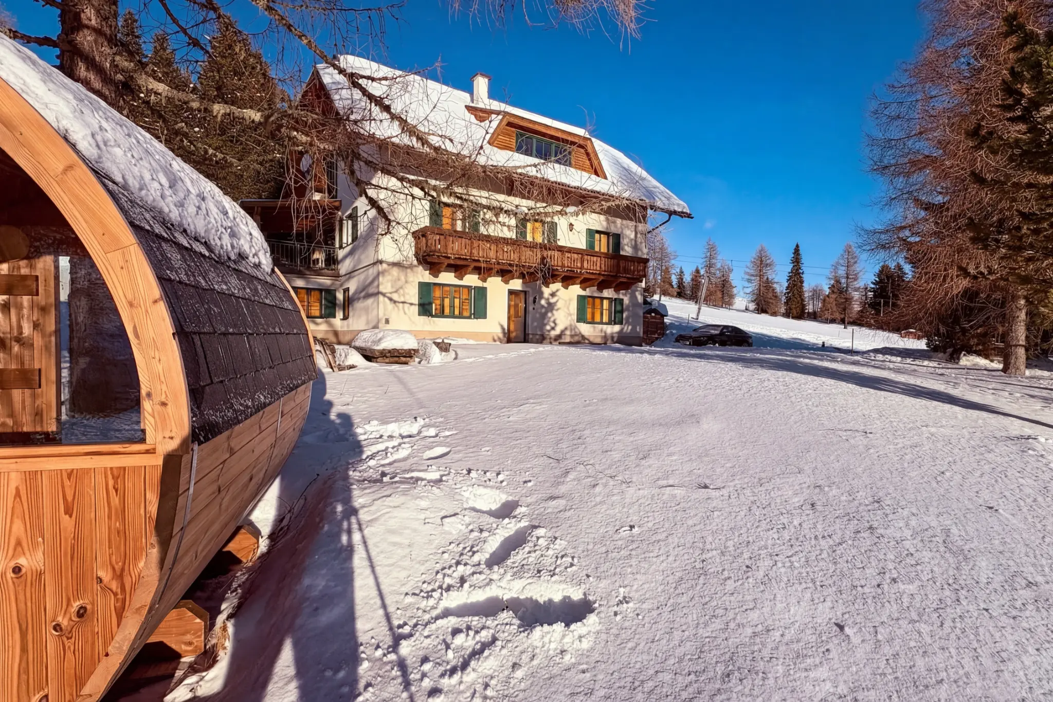 Berglodge Hochrindl and private barrel sauna in the snow-covered winter garden