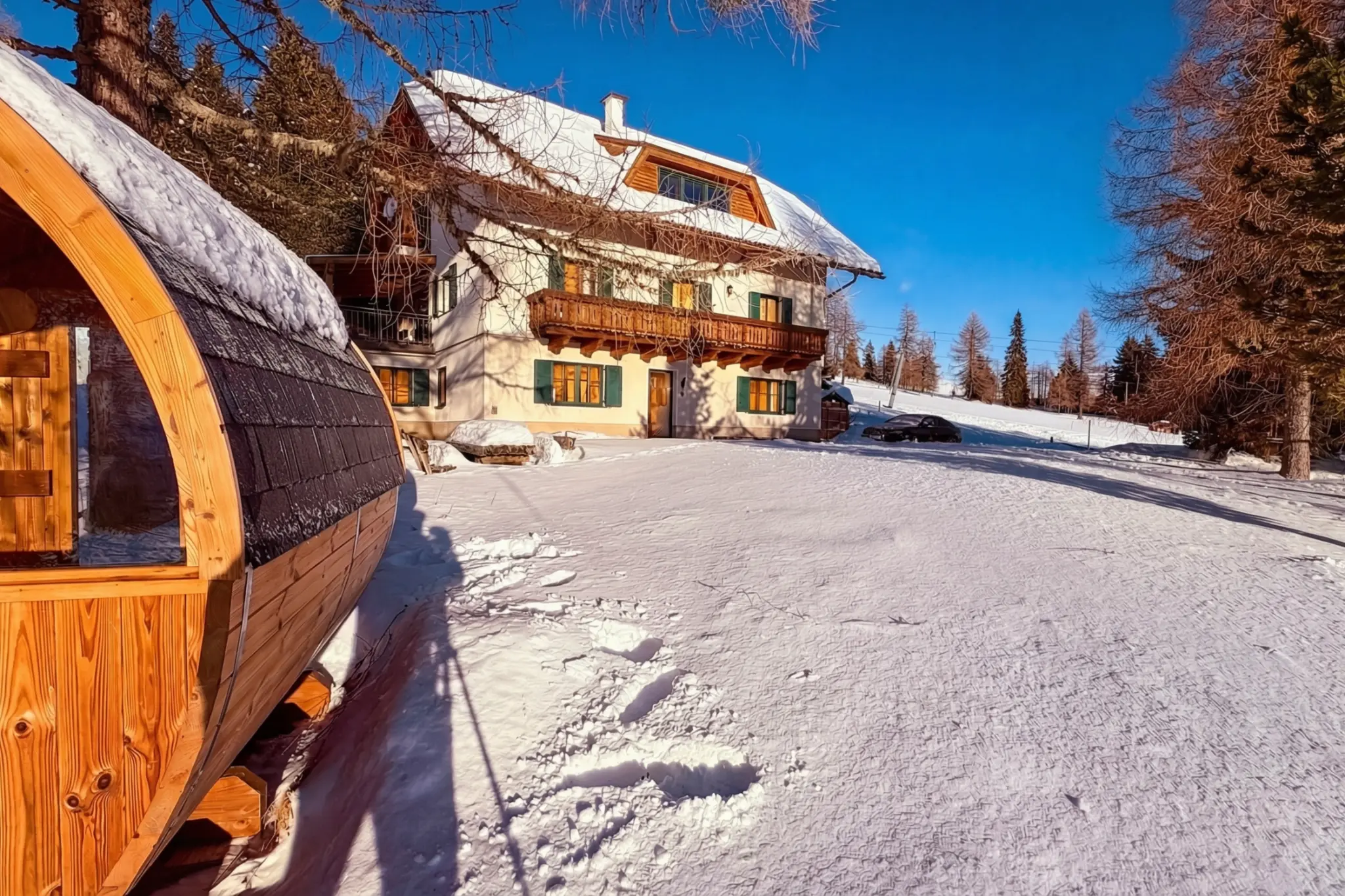 Berglodge Hochrindl in winter with private barrel sauna in the foreground