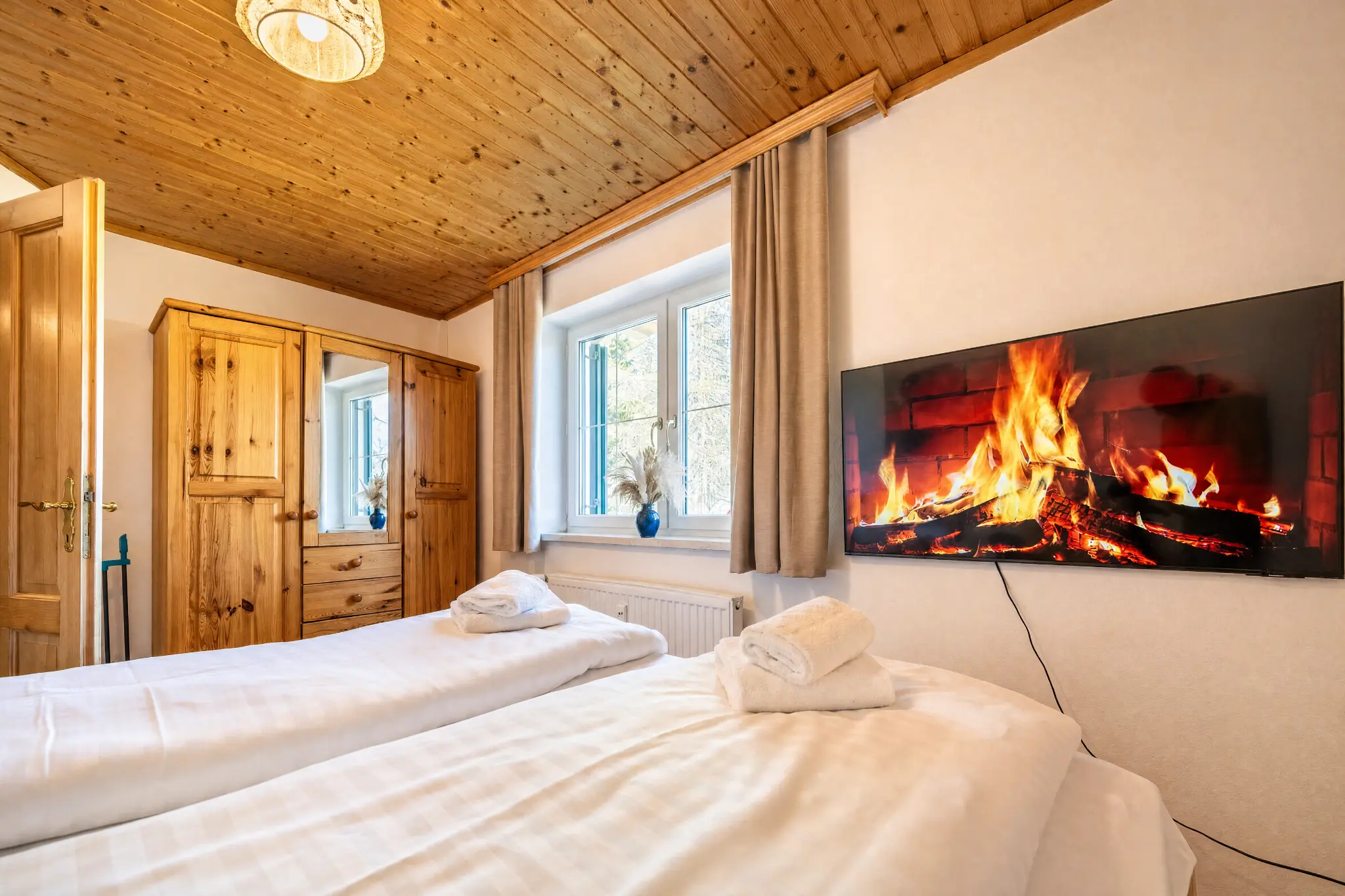 Schlafzimmer 2 Berglodge Hochrindl — Kingsize-Bett mit Kamin-Screen
